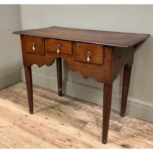 446 - An 18th century oak side table having three small drawers to the arched and shaped apron, on rounded... 