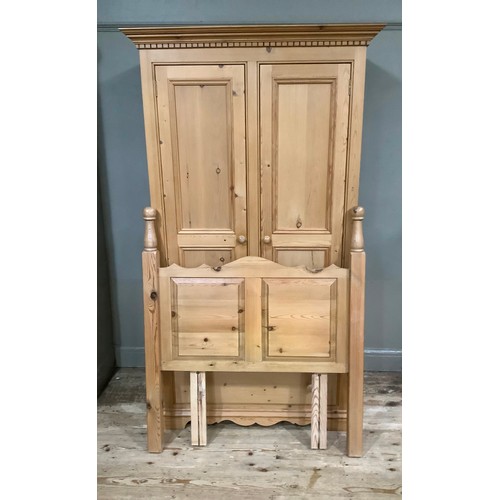 401 - A pine wardrobe having a moulded and dentil cornice above two indented panel doors with drawers belo... 