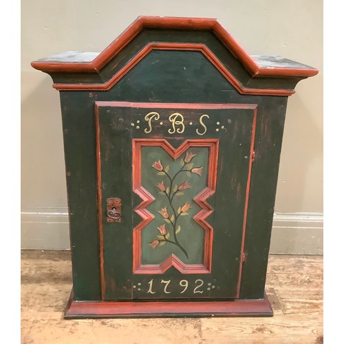 409 - A green painted wall cabinet having an arched cornice above a single door with indented panel painte... 