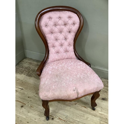 434 - A Victorian mahogany nursing chair having pink buttoned upholstery and on cabriole legs with casters