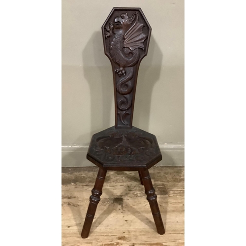 405 - An 19th century oak spinning chair carved in relief with dragons to the back and seat