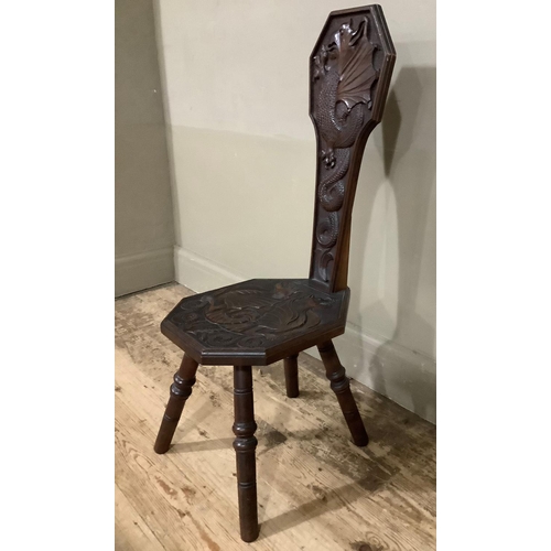 405 - An 19th century oak spinning chair carved in relief with dragons to the back and seat