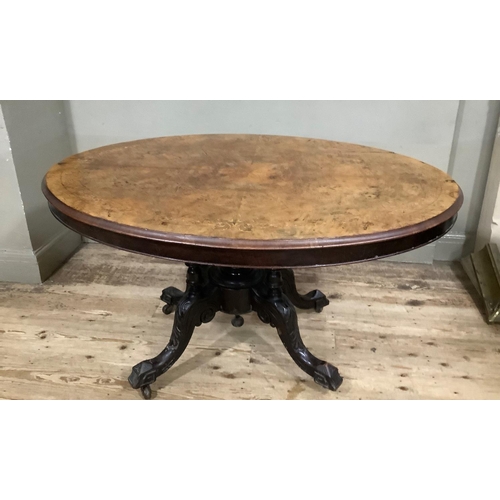 411 - A Victorian figured walnut looe table of oval outline on four column pedestal and foliate carved cab... 