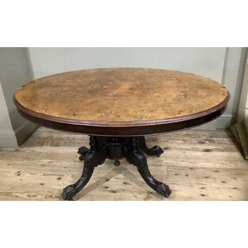 411 - A Victorian figured walnut looe table of oval outline on four column pedestal and foliate carved cab... 