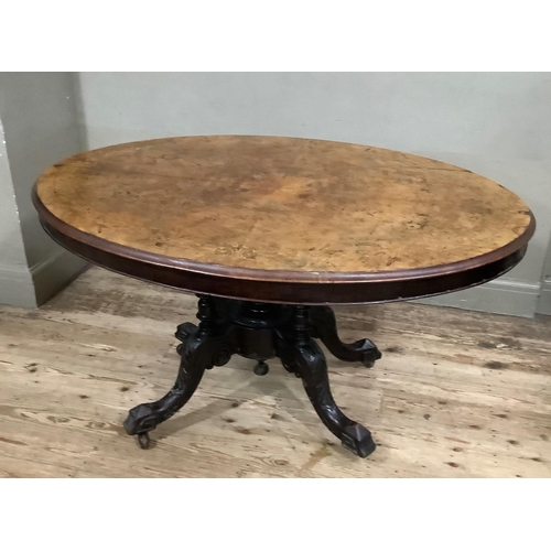 411 - A Victorian figured walnut looe table of oval outline on four column pedestal and foliate carved cab... 