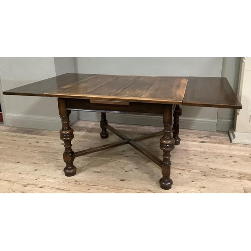 416 - A 1920s oak drawer leaf dining table on turned legs with cross stretchers and on compressed circular... 