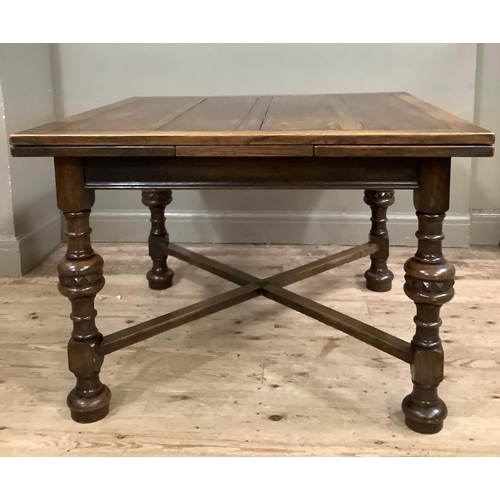 416 - A 1920s oak drawer leaf dining table on turned legs with cross stretchers and on compressed circular... 