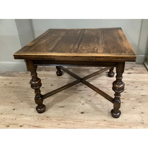 416 - A 1920s oak drawer leaf dining table on turned legs with cross stretchers and on compressed circular... 