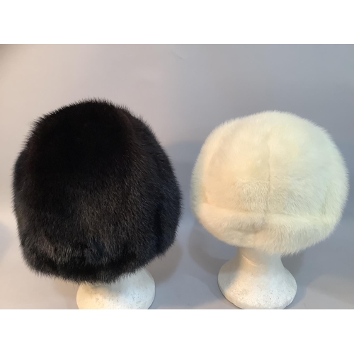 226 - Two Phillip Somerville winter hats,  in black-glama mink c.1977 and a white mink c.1979, both in hat... 