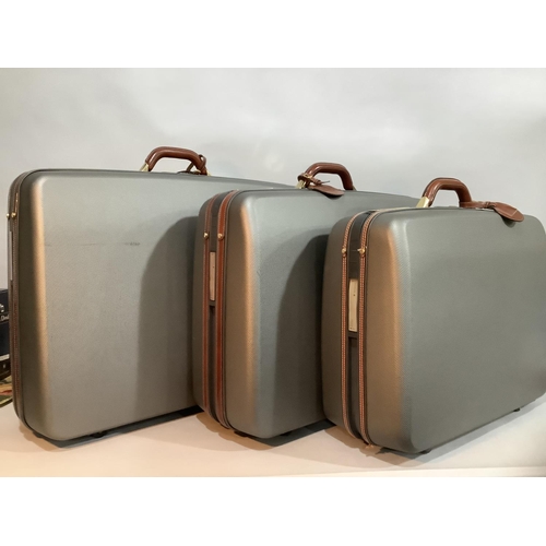 221 - Three Samsonite hard shell grey and leather suitcases with pull-along handles and wheels