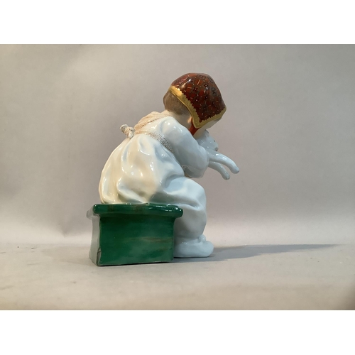 33 - A Meissen porcelain figure after Konrad Hentschel of a girl sat on green box with a cat in her arms,... 