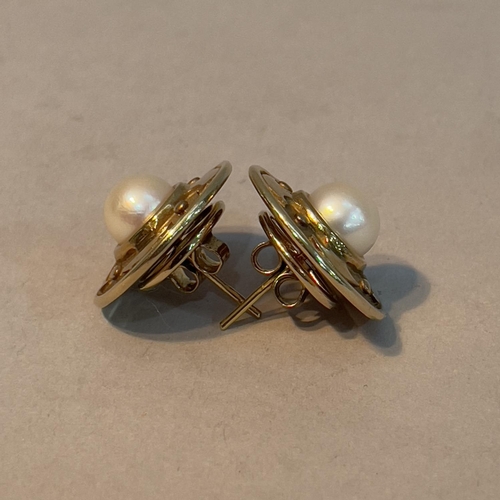 350 - A pair of cultured pearl ear studs in 9ct gold each set with a 7mm pearl raised against textured and... 