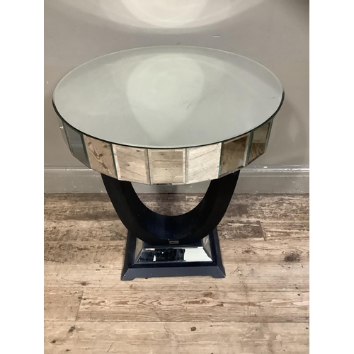 365 - A mirrored occasional table of circular outline on a black u-shaped support, mirrored and black plin... 