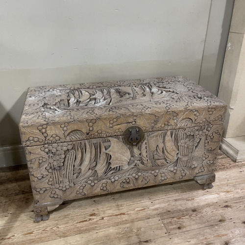 376 - A camphor wood chest all over carved with junks and fruiting leaves, circular lock plate and on brac... 