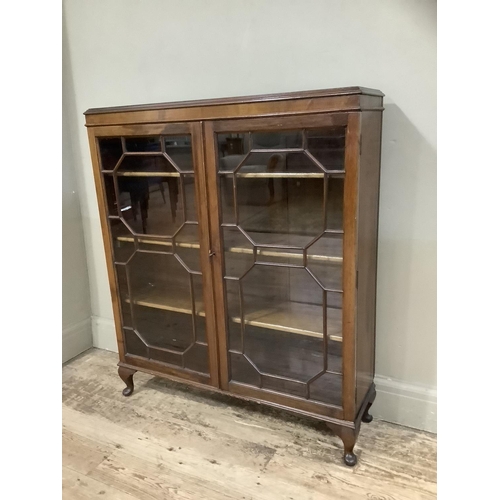 398 - A mid 20th century mahogany and glazed bookcase  having two tracery glazed doors and on short cabrio... 