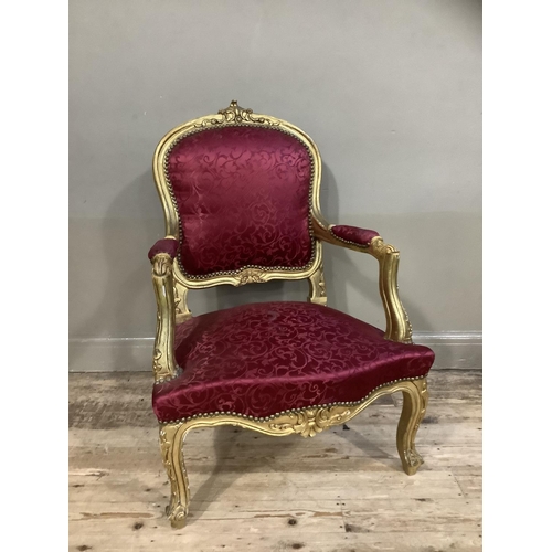 406 - A Victorian style gilt armchair having an encircling frame, red fabric upholstered back and seat, on... 