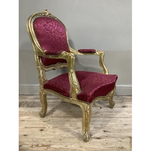 406 - A Victorian style gilt armchair having an encircling frame, red fabric upholstered back and seat, on... 