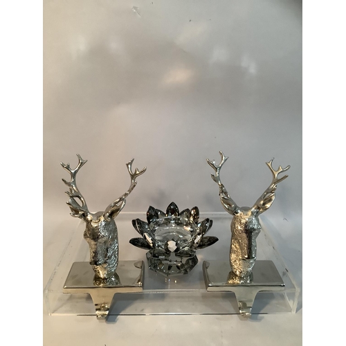 73 - A pair of white metal table hooks formed as stags together with a moulded glass candle holder in the... 