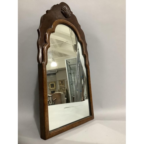 390 - An early 20th century walnut shield shaped mirror having a carved shell pediment, 57cm x 33cm