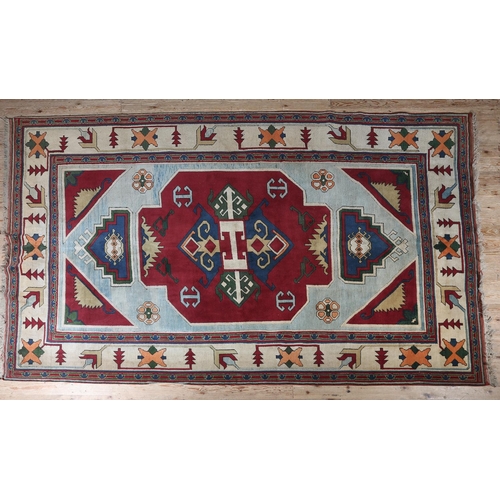 107 - A Kazak carpet, the pale blue ground having a maroon panel and spandrels filled with geometric motif... 