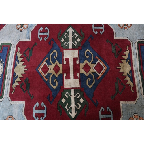 107 - A Kazak carpet, the pale blue ground having a maroon panel and spandrels filled with geometric motif... 