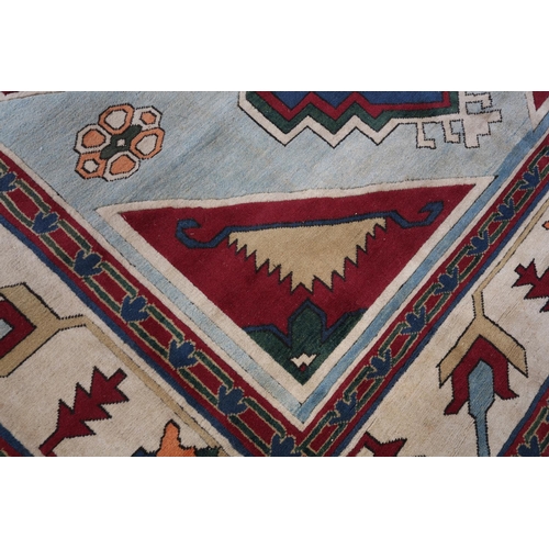 107 - A Kazak carpet, the pale blue ground having a maroon panel and spandrels filled with geometric motif... 