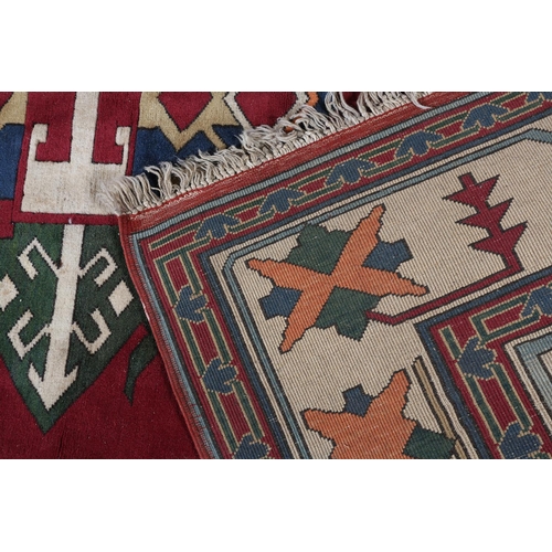 107 - A Kazak carpet, the pale blue ground having a maroon panel and spandrels filled with geometric motif... 