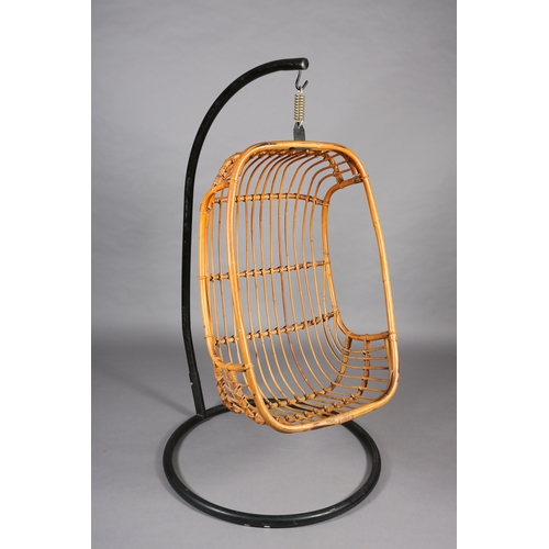 116 - A rattan basket swing chair, pendant from a black metal tubular frame