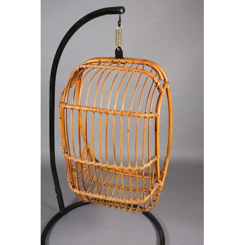 116 - A rattan basket swing chair, pendant from a black metal tubular frame