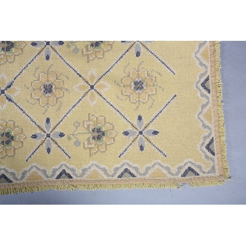 54 - A mid century needlwork tapestry style rug with blue squares containing florettes on a mustard groun... 