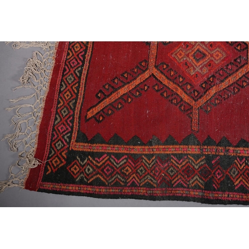 104 - A Middle Eastern carpet, the wine ground filled with a panel of multiple diamond motifs, filled with... 