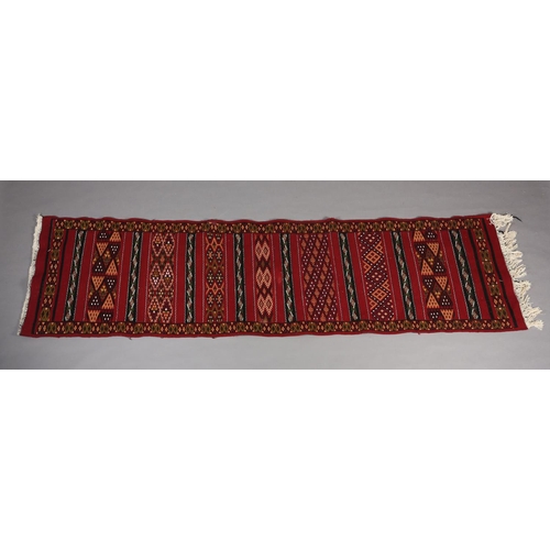 138 - A Middle Eastern kilim runner, the wine ground with alternating horizontal panels of orange, white, ... 