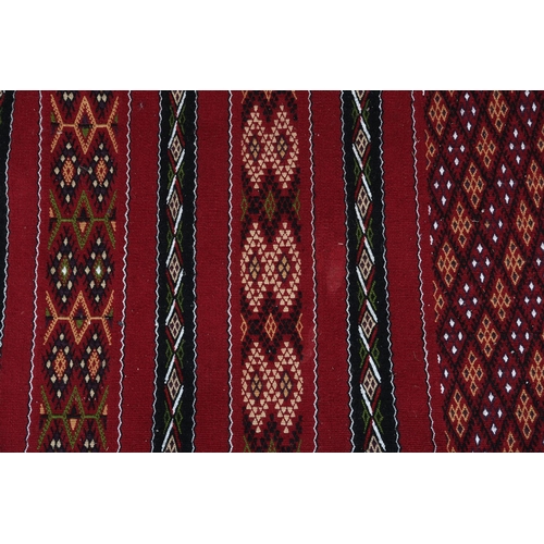 138 - A Middle Eastern kilim runner, the wine ground with alternating horizontal panels of orange, white, ... 