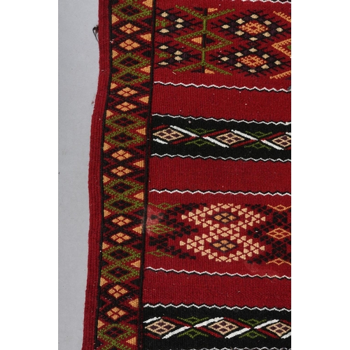 138 - A Middle Eastern kilim runner, the wine ground with alternating horizontal panels of orange, white, ... 