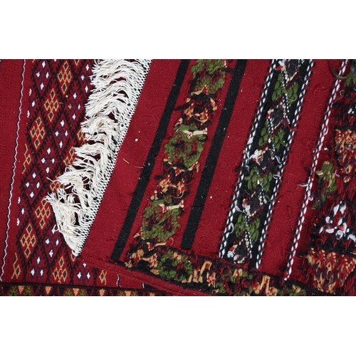 138 - A Middle Eastern kilim runner, the wine ground with alternating horizontal panels of orange, white, ... 