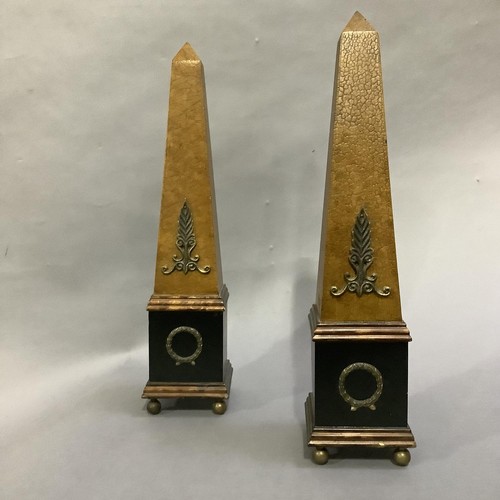 124 - A pair of ebonised and faux leather obelisks on ball feet, 48cm high