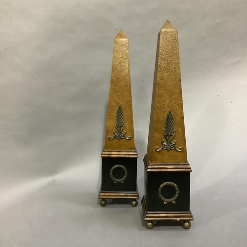 124 - A pair of ebonised and faux leather obelisks on ball feet, 48cm high