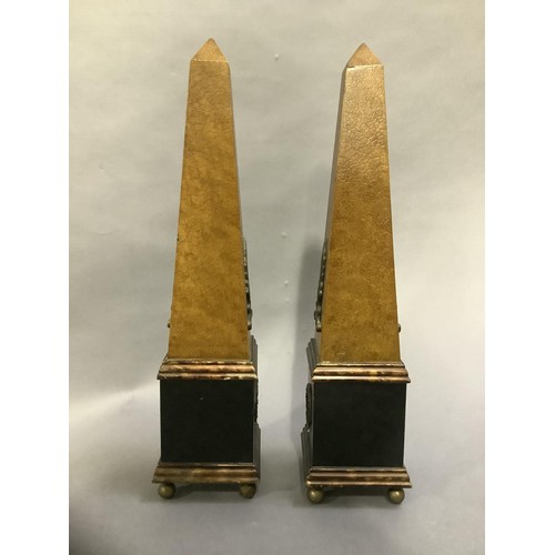 124 - A pair of ebonised and faux leather obelisks on ball feet, 48cm high