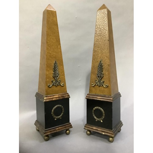 124 - A pair of ebonised and faux leather obelisks on ball feet, 48cm high