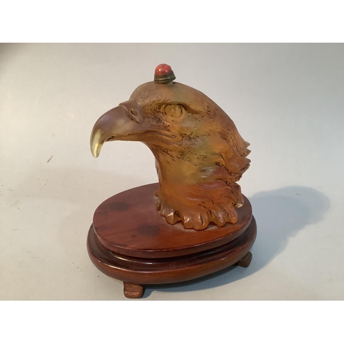 27 - A Chinese amber coloured glass eagle head snuff bottle, mounted on a stand, 11.5cm high