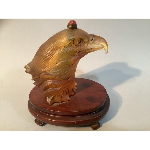 27 - A Chinese amber coloured glass eagle head snuff bottle, mounted on a stand, 11.5cm high