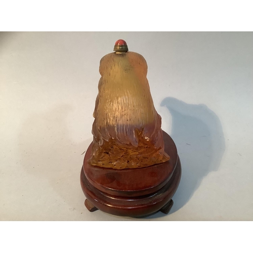 27 - A Chinese amber coloured glass eagle head snuff bottle, mounted on a stand, 11.5cm high