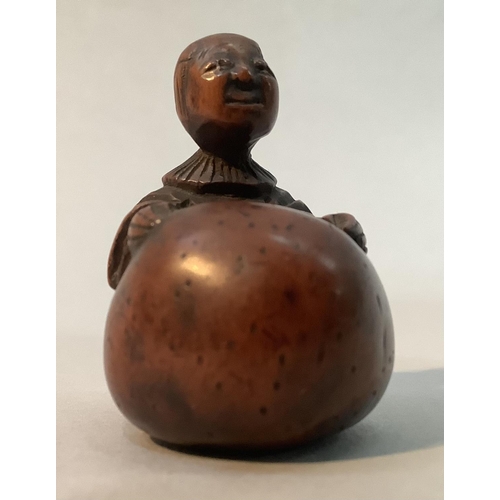 350 - A Japanese fruitwood netsuke carved as a man standing with his arms stretched around a large gourd, ... 