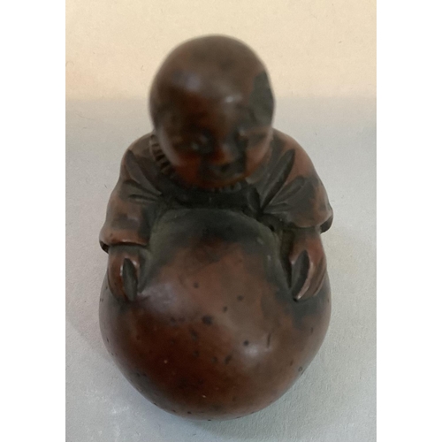 350 - A Japanese fruitwood netsuke carved as a man standing with his arms stretched around a large gourd, ... 