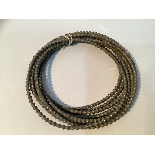 355 - A set of nine rings of metal faceted beads, strung on a coiled metal strand, approximate possibly Bu... 