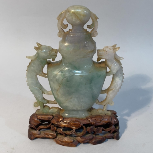 62 - A Chinese jade vase and cover, of urn outline with twin dragon handles, on hardwood stand, 14.5cm