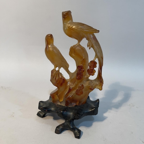 64 - A Chinese amber agate carving of birds perched on a tree stump, with hardwood stand, 16.5cm high