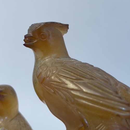 64 - A Chinese amber agate carving of birds perched on a tree stump, with hardwood stand, 16.5cm high