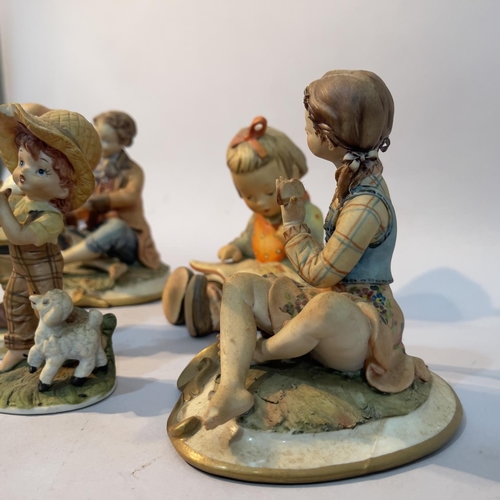 241 - A Capodimonte figures of a boy and girl seated, two Hummel figures and another continental figure