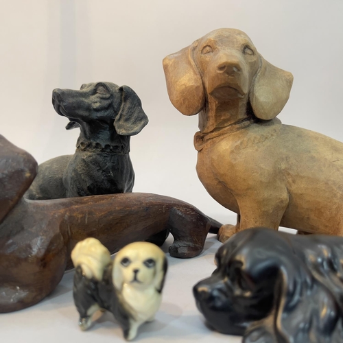 218 - Two wooden carved dachshunds, a composite spaniel and a dachshund money box